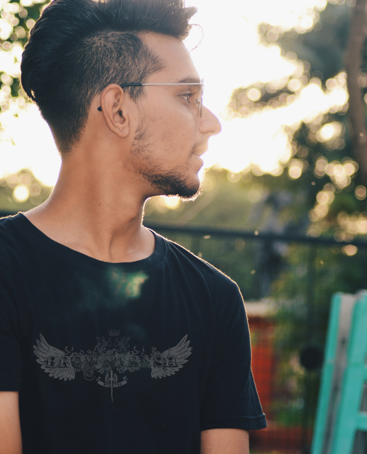 South Asian Male Model wearing black fitted tshirt with Brown Trash silkscreened graphic design image on front.