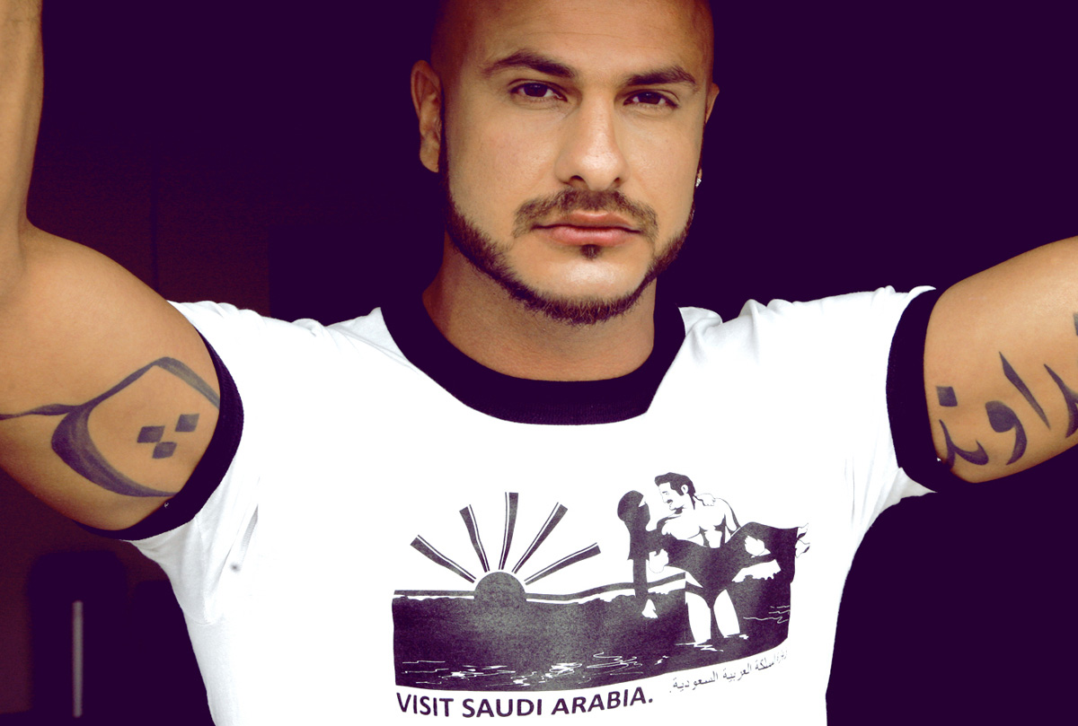 Shop Men Graphic Design Tshirts. Male Model with Arabic tatoos on arms wearing Visit Saudi Arabia tshirt.